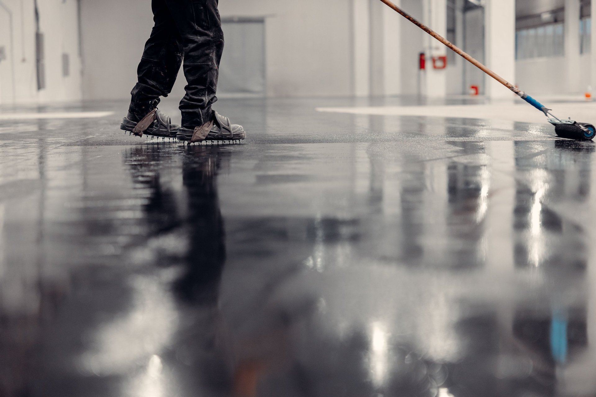 Large industrial workspace with a seamless epoxy resin floor being levelled with a roller
