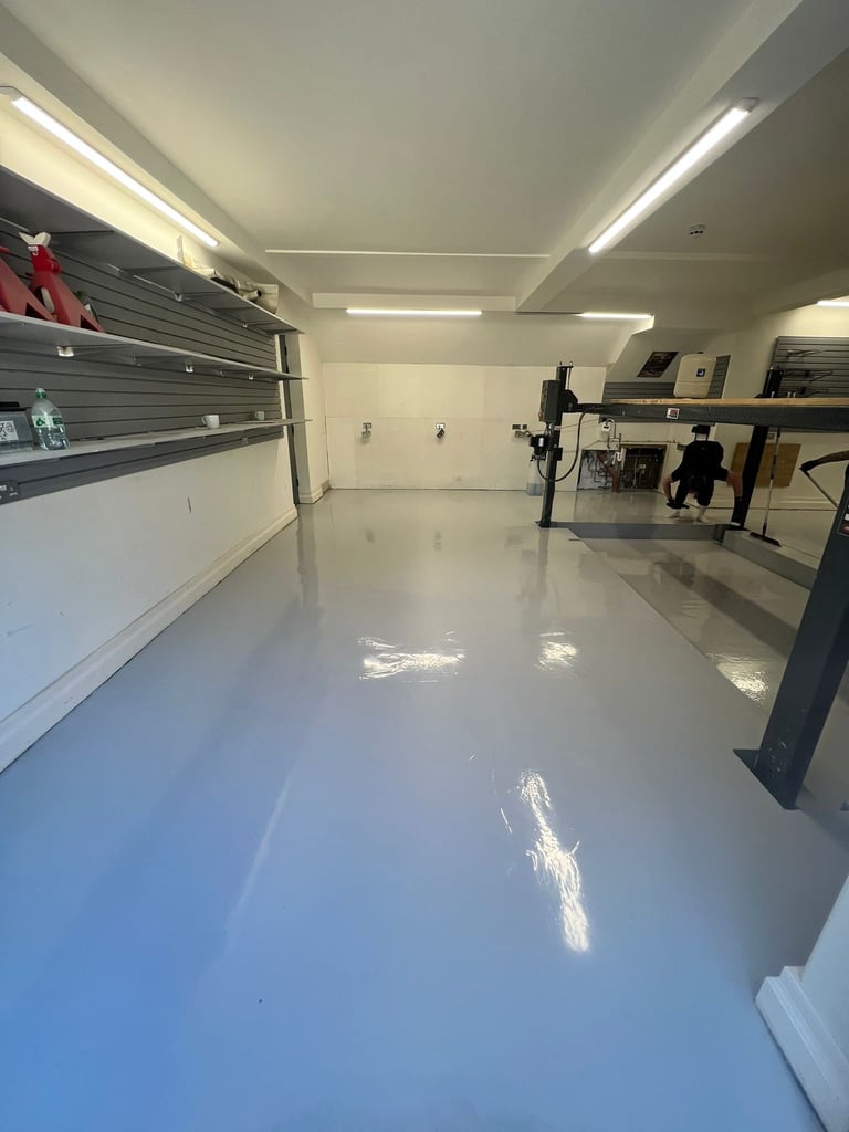 Empty retail or commercial space with glossy white floor, pegboard wall display, LED ceiling lights, and equipment on the right side