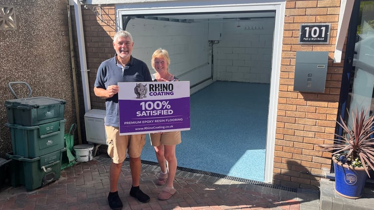Two people standing in front of a garage holding a Rhino Gutter Guard customer satisfaction sign